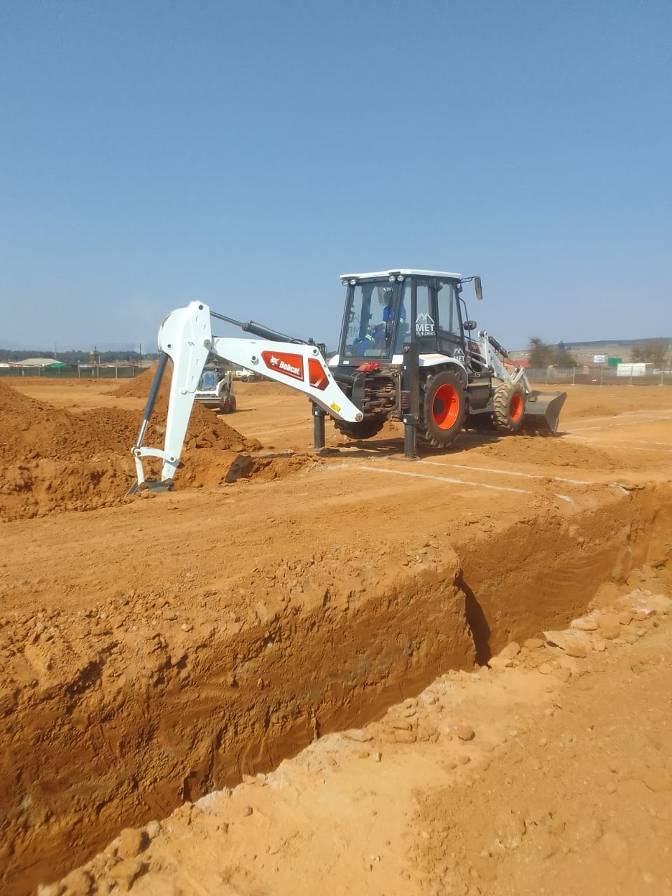 MET Builders Bobcat excavating foundation trenches at Three Fountains Mall