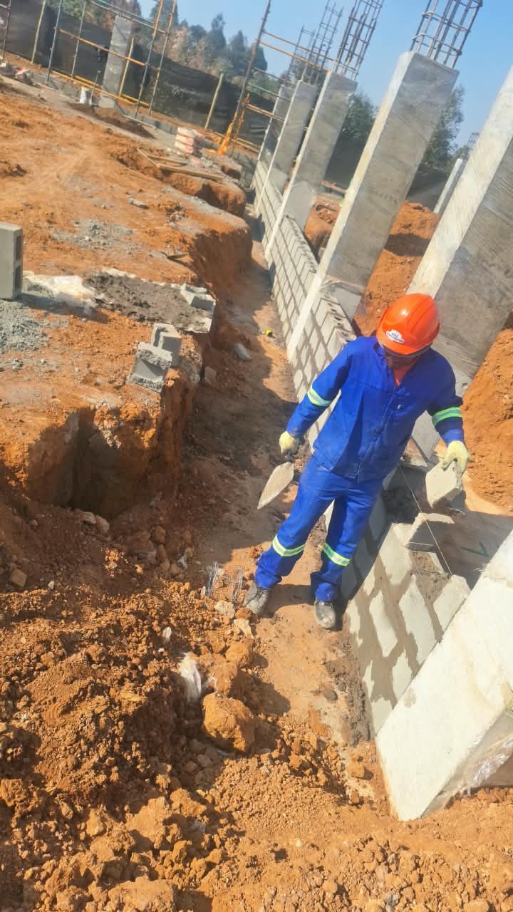 Mason laying concrete blocks at column base, Three Fountains Shopping Centre, September 2026